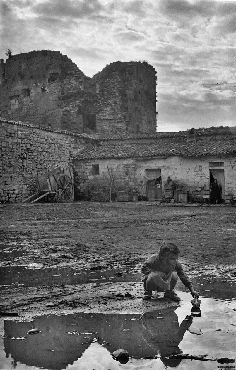 Young Girl Playing with a Paper Boat in a Puddle Surrounded by Mud, Venosa, Basilicata, Italy by Ando Gilardi