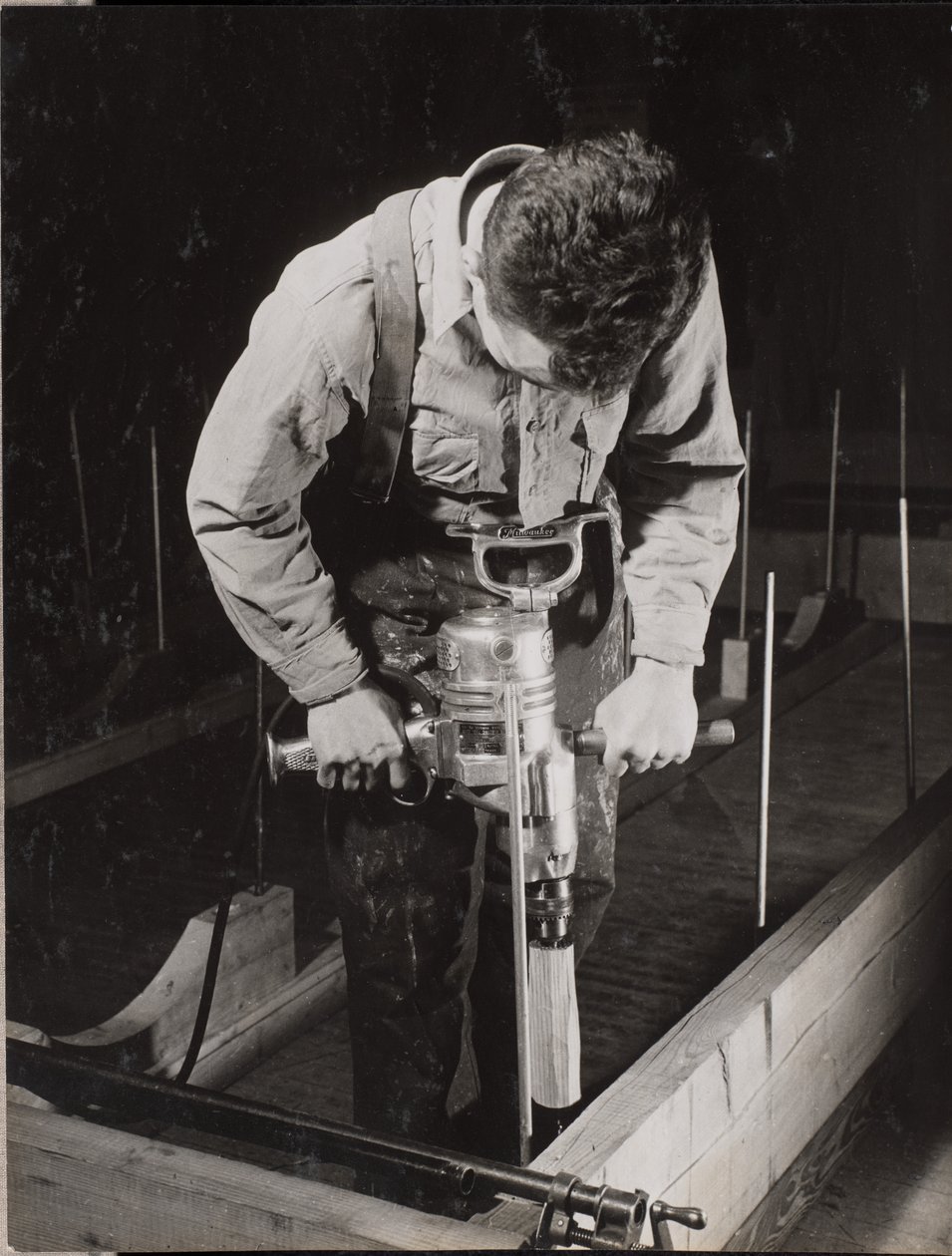 Man uses a handheld machine to work with a piece of wood by Arnold Eagle