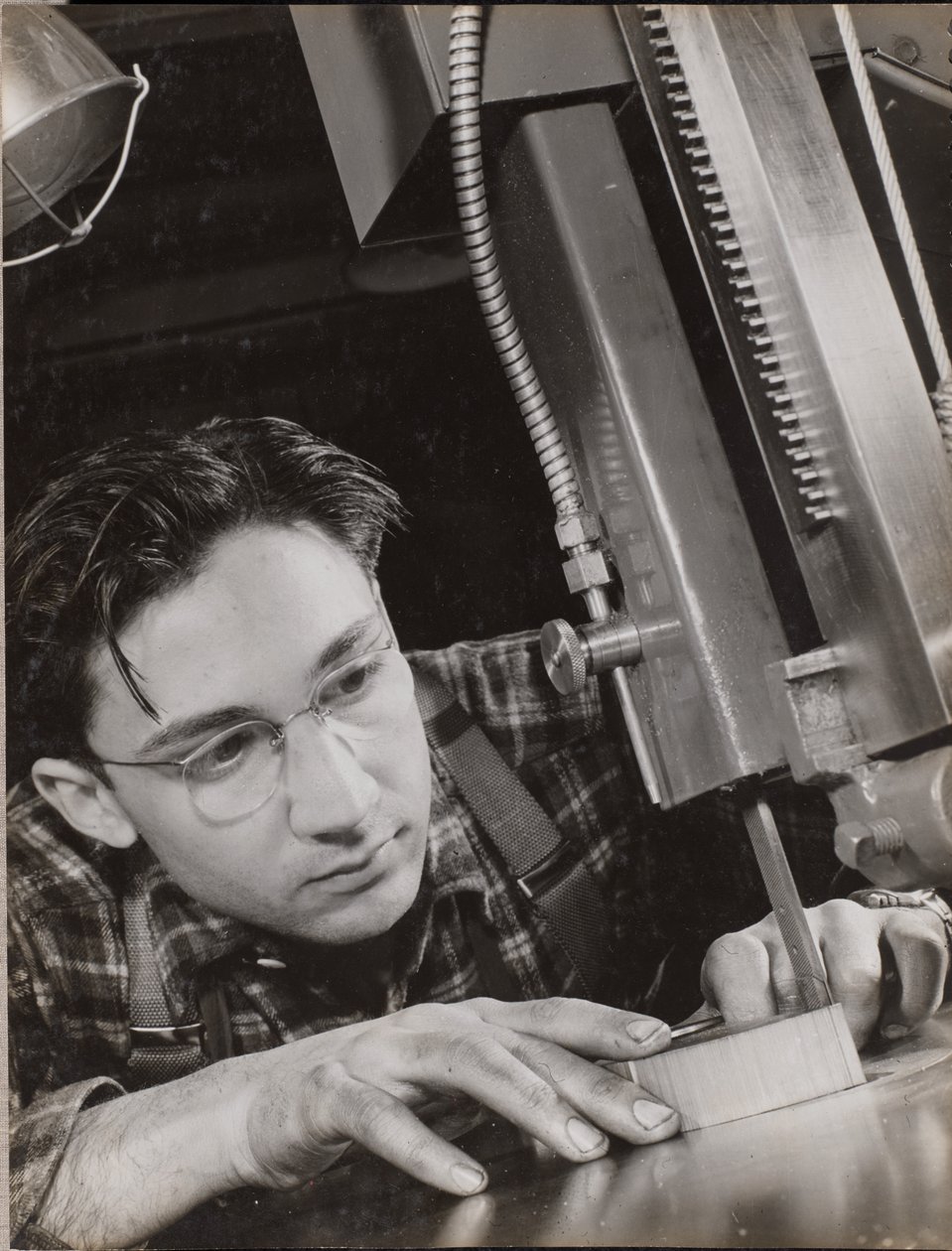 Man wearing glasses working with an industrial file by Arnold Eagle