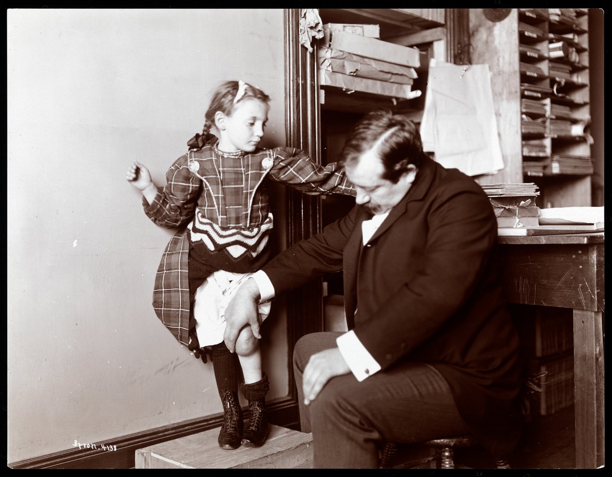 Professor Atkinson, an English bone setter, with a young female patient, 1898 by Byron Company
