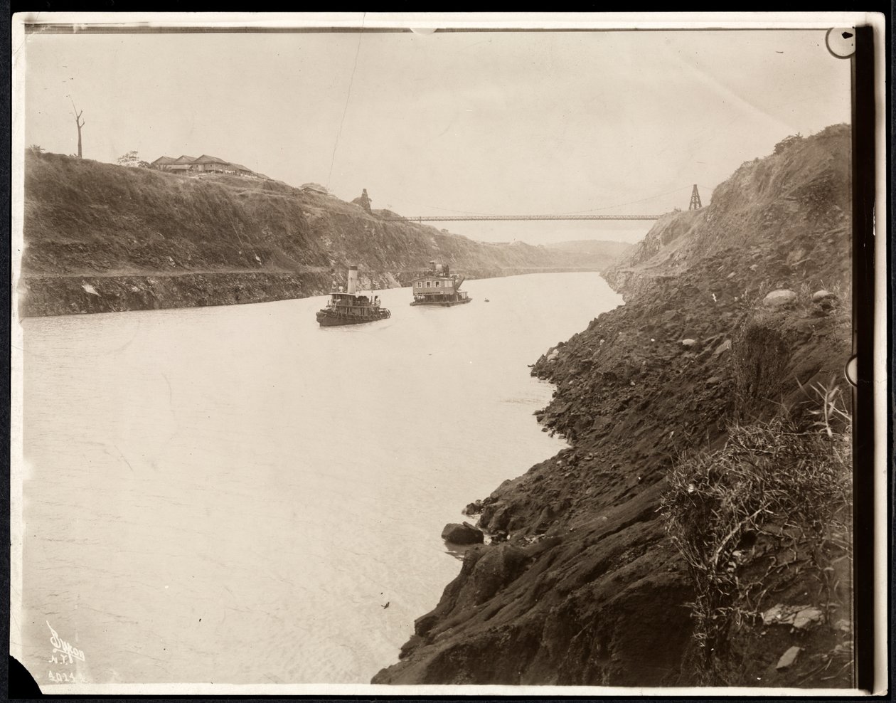 View of Two Boats in the Panama Canal During its Construction with a Suspension Bridge Beyond, 1913 by Byron Company