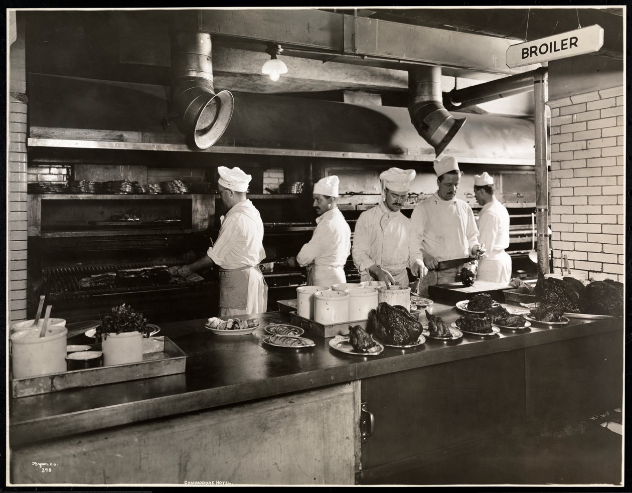 Cooks at the broiler in the kitchen of the Hotel Commodore, 1919 by Byron Company