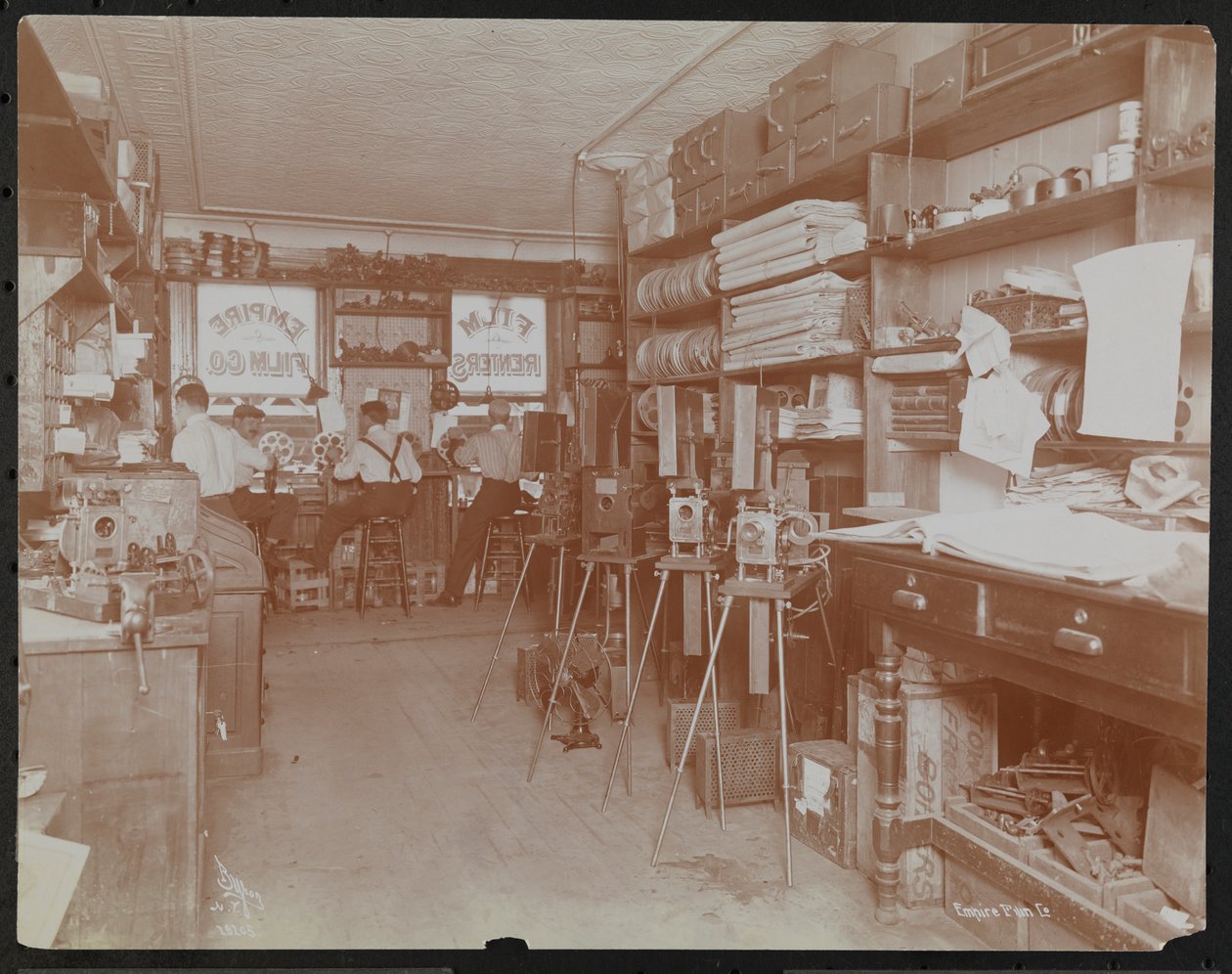 Empire Film Co. motion picture laboratory with men working and reels of film and cameras by Company Byron