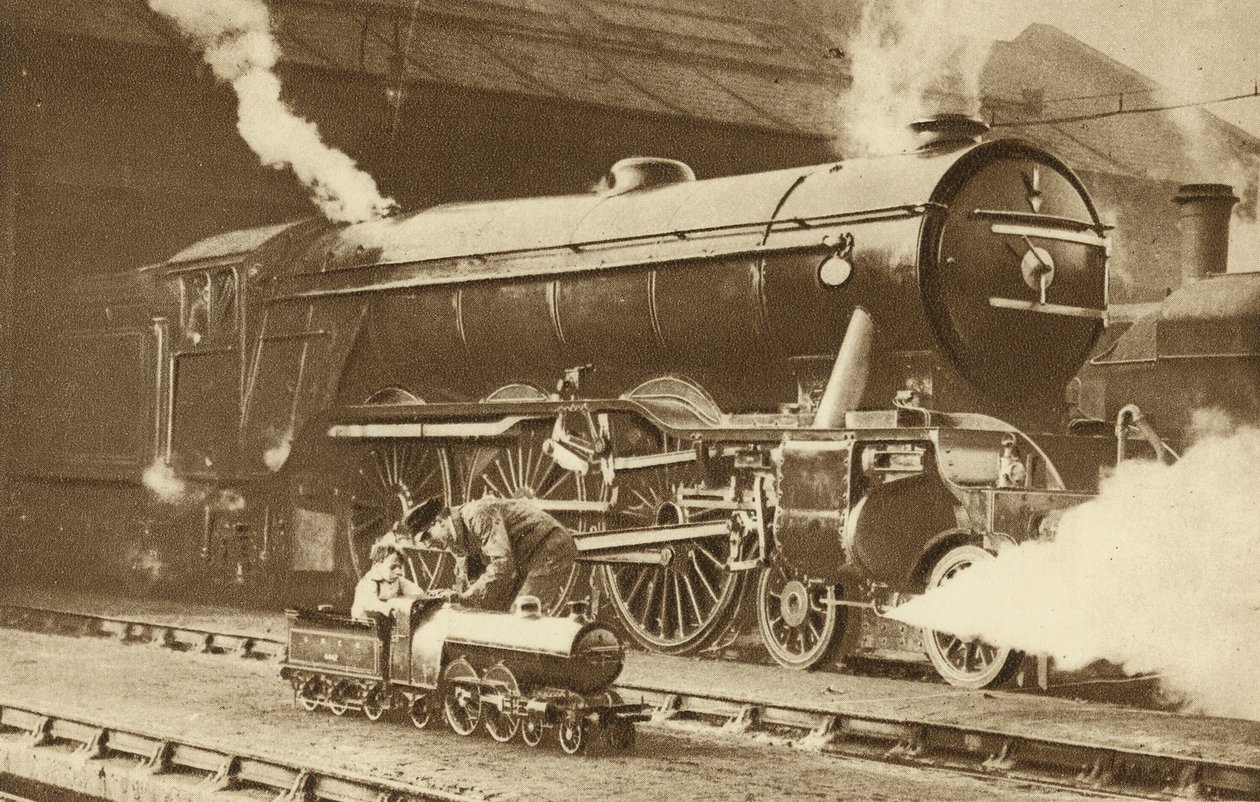 Boy riding a toy steam locomotive in front of the real thing by English Photographer