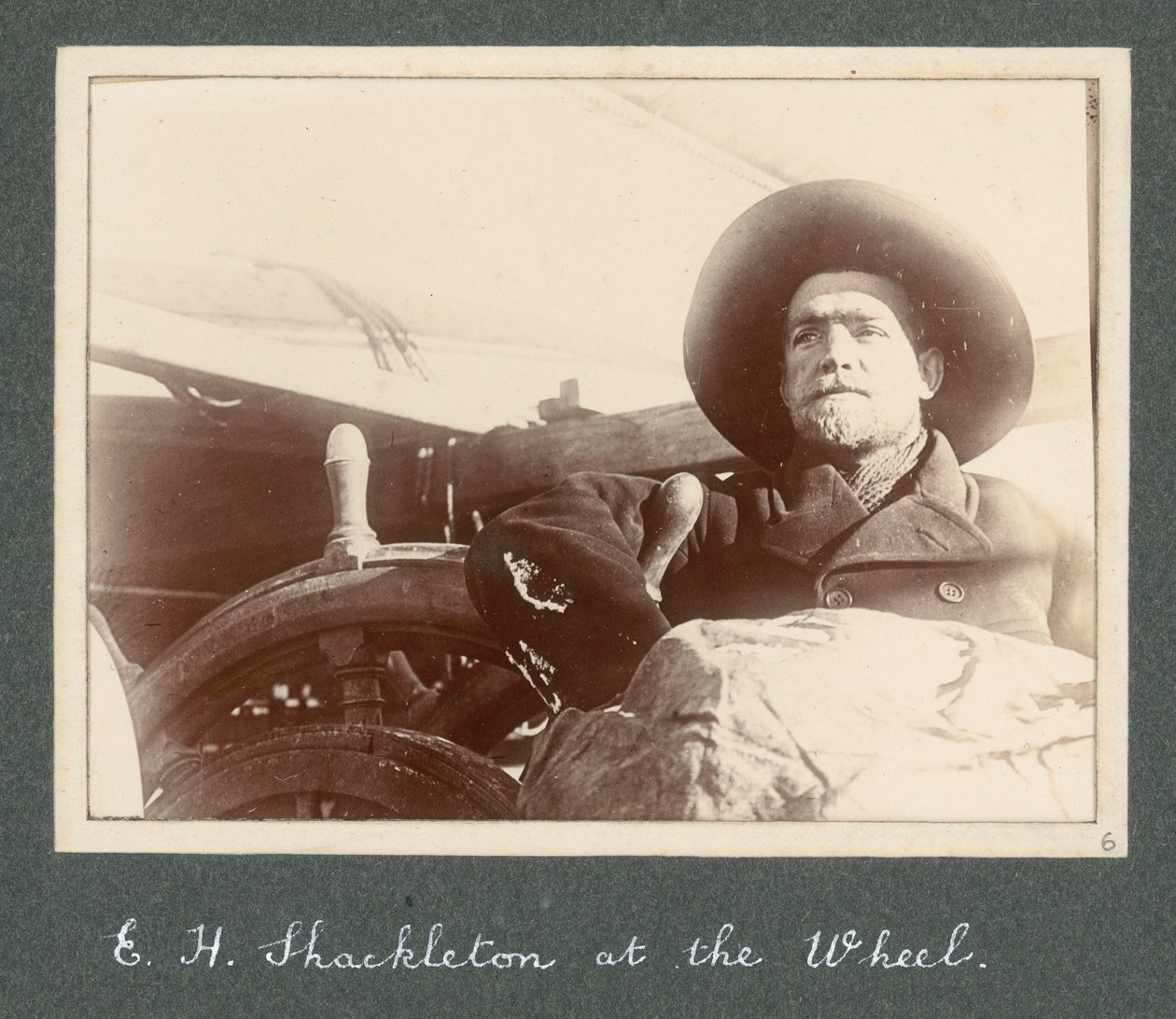 E H Shackleton standing by wheel of the 