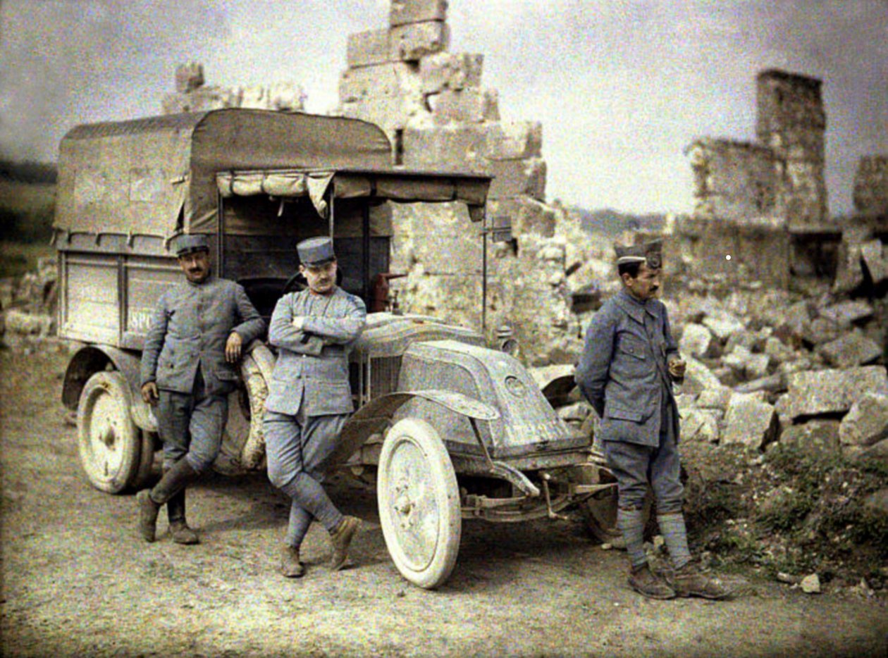 Three French soldiers parked in front of a heavily damaged building with a small truck, Aisne, France by Fernand Cuville