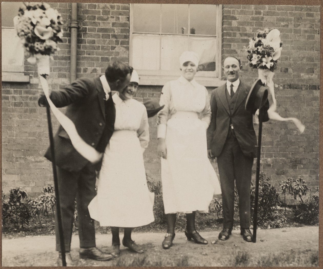 Two men holding tutti poles with two women during the Hocktide Festival in Hungerford by George R. Long