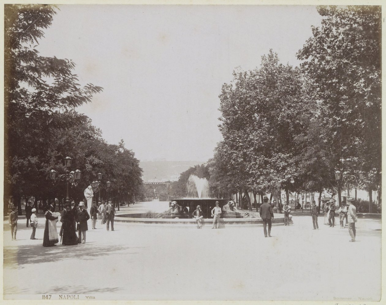 Square with a Fountain and Strolling People in Naples by Giorgio Sommer