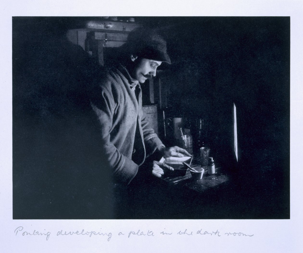 Ponting developing a plate in the dark room, from 
