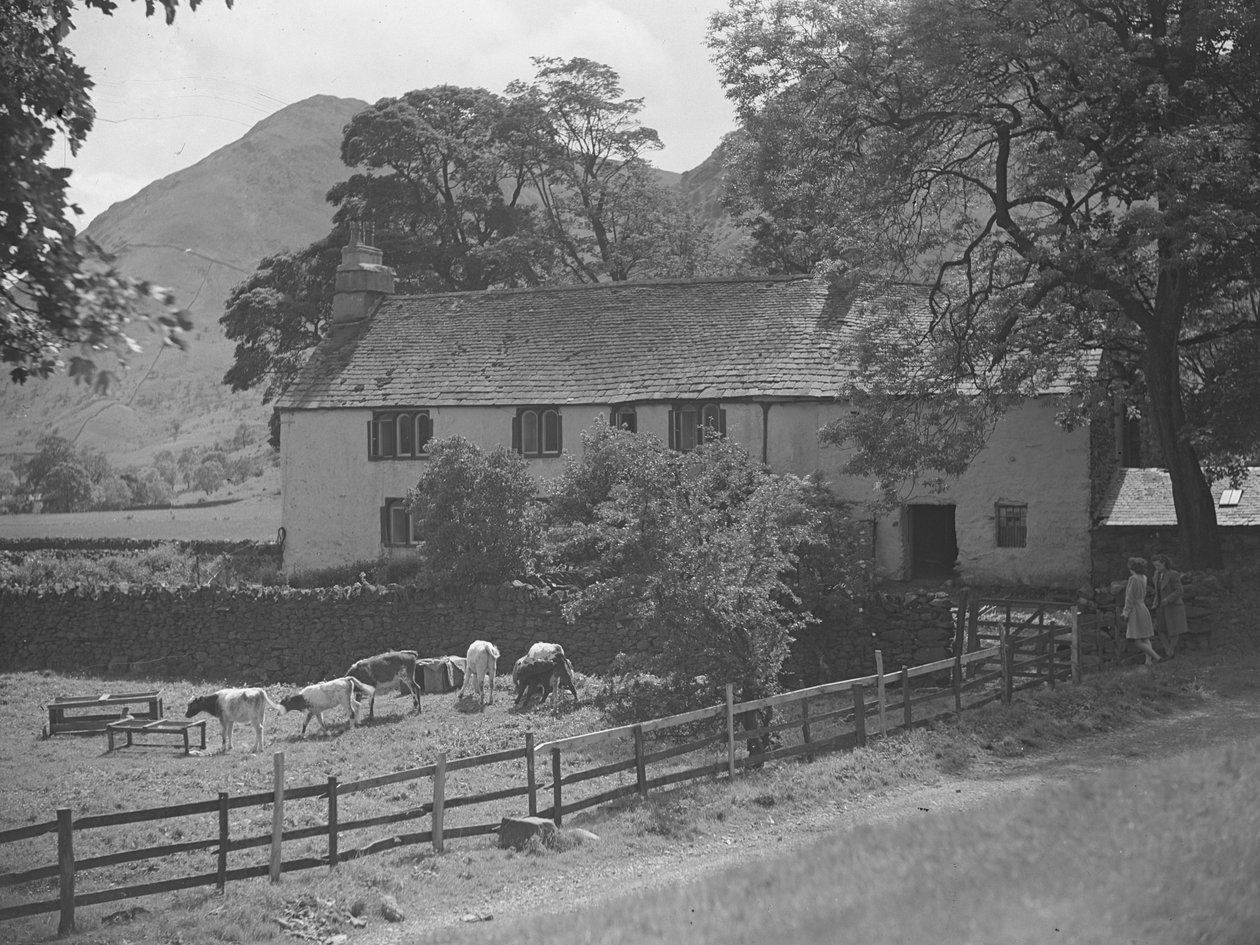 A building in front of which there are calves grazing, to the right two women stood talking against a wall and hills in the background by Joseph Hardman