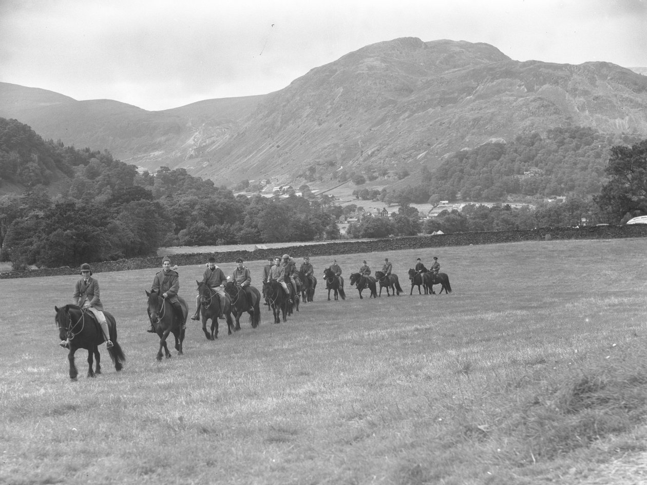 A group of men trekking in a line on ponies, fells in the background by Joseph Hardman