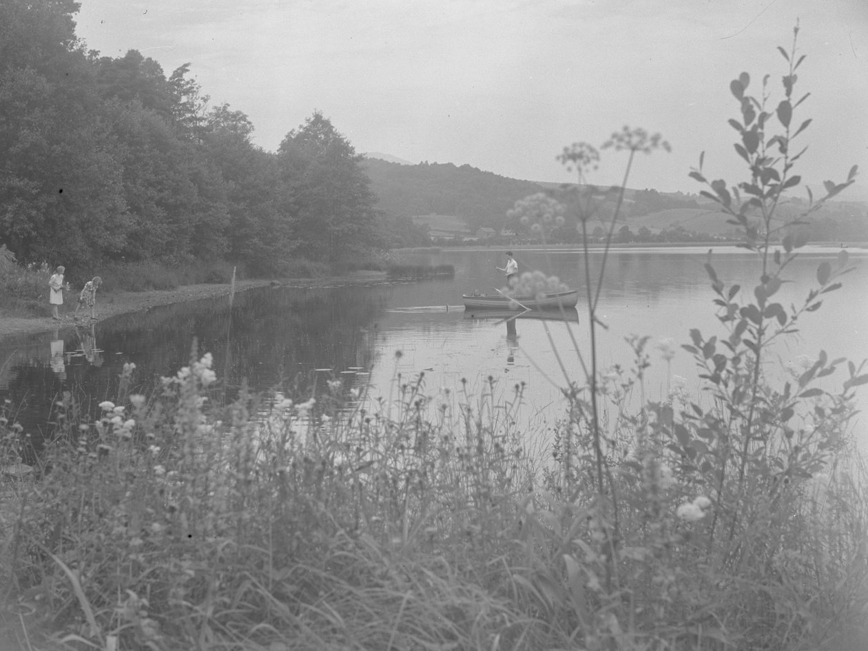 Man fishing in a boat on Esthwaite Water and two girls at the water