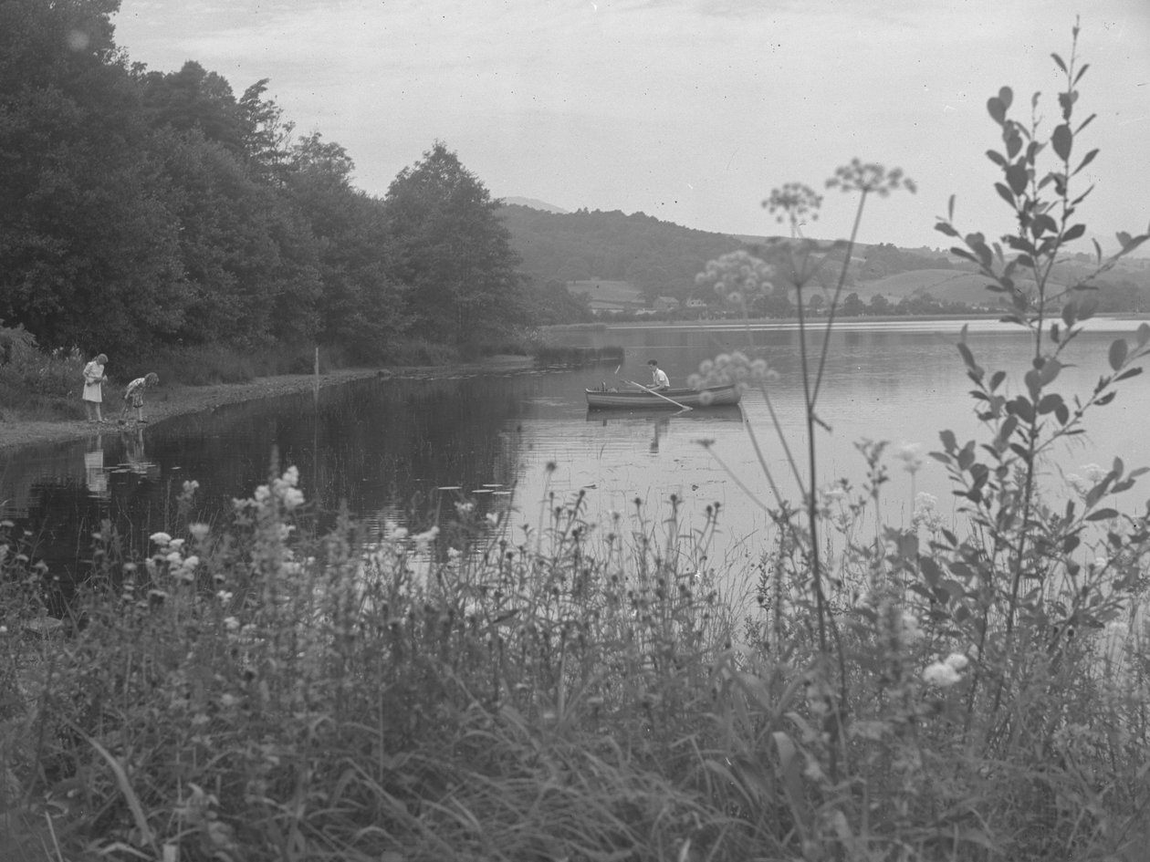 Man fishing in a boat on Esthwaite Water and two girls at the water