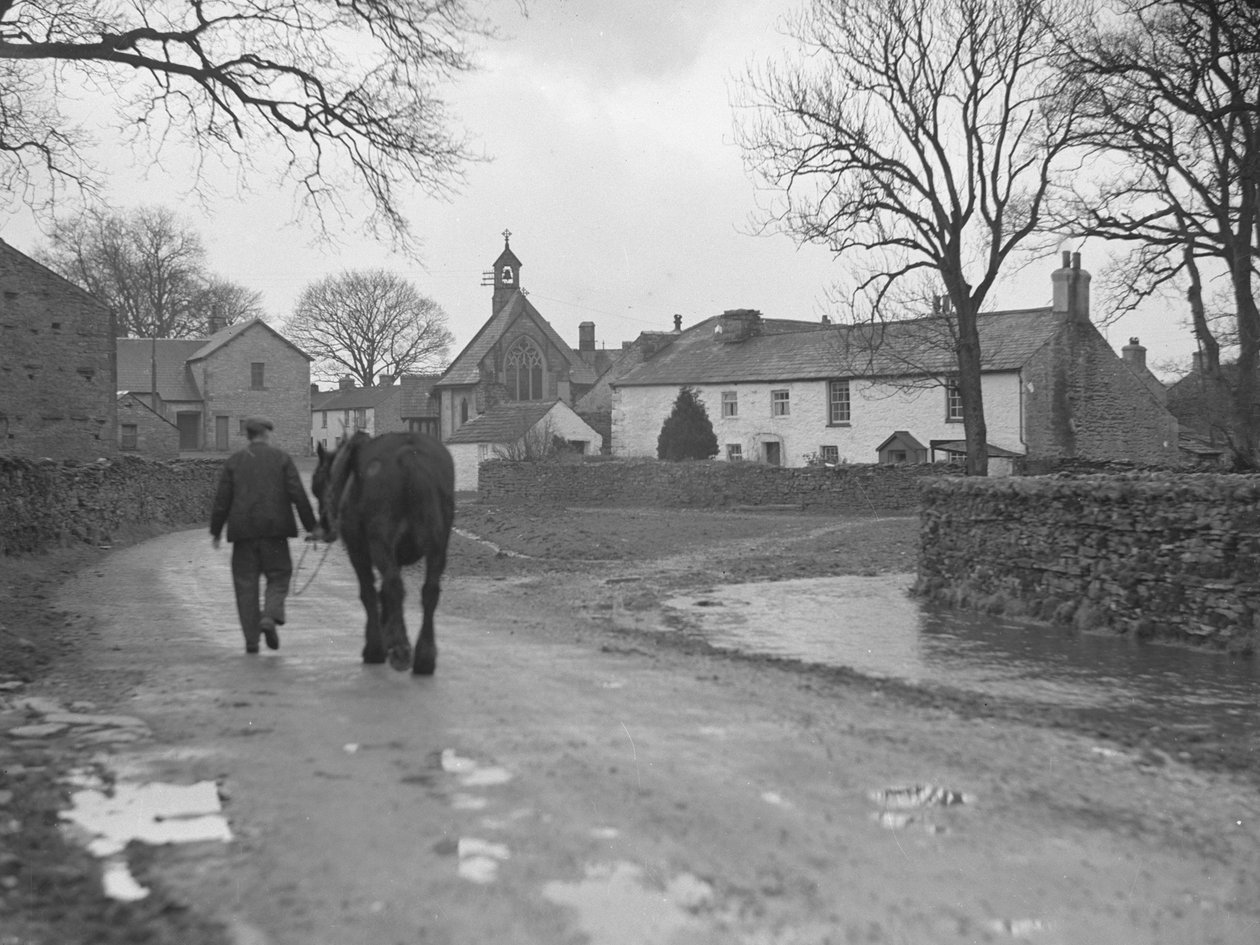 Man leading horse down road toward village buildings and church by Joseph Hardman