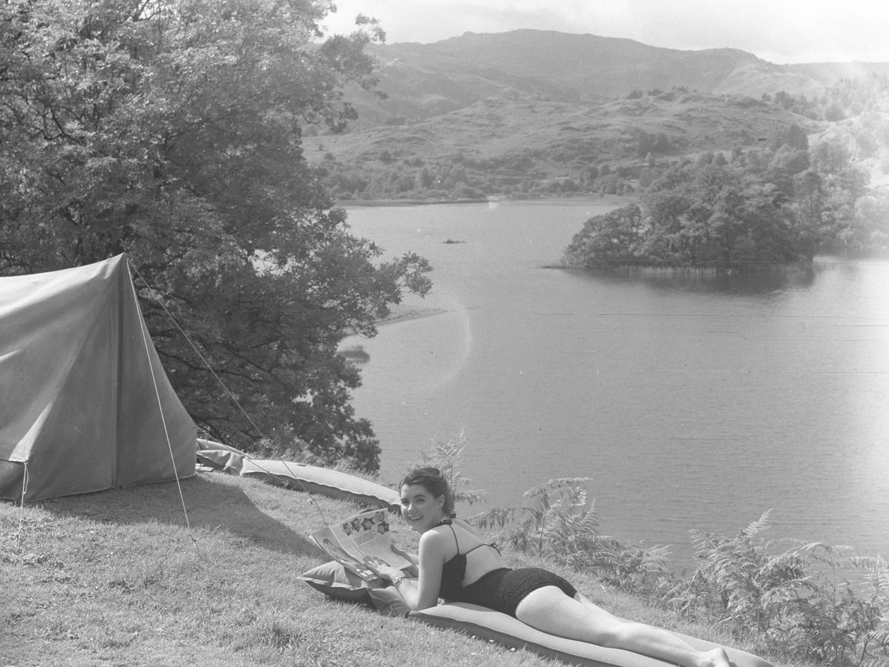 View of young woman wearing a swimming costume and lying on a lilo, lake in background by Joseph Hardman