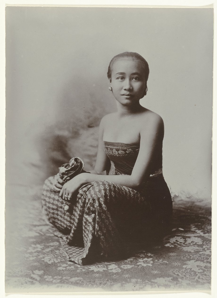 Studio portrait of a seated young Javanese woman in a sarong with batik motif by Kassian Cephas