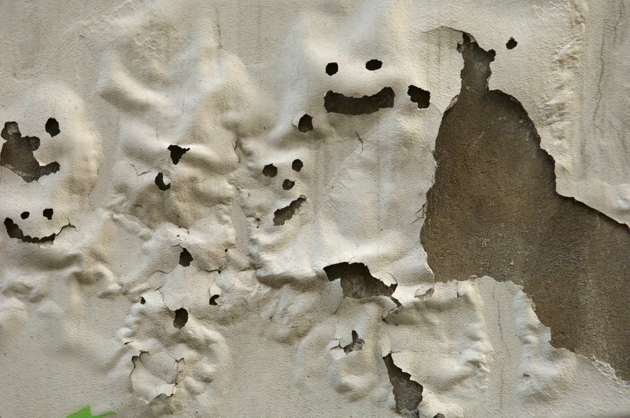 Smiley ghost faces on weathered painted wall, 2022 (photo) by Sisse Brimberg