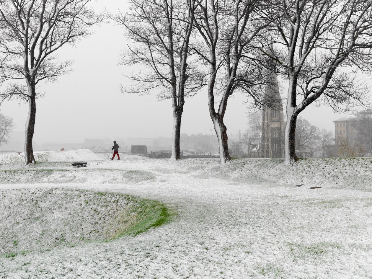 Lone figure walking in Copenhagen Fortress during snowstorm, Denmark, 2022 by Sisse Brimberg