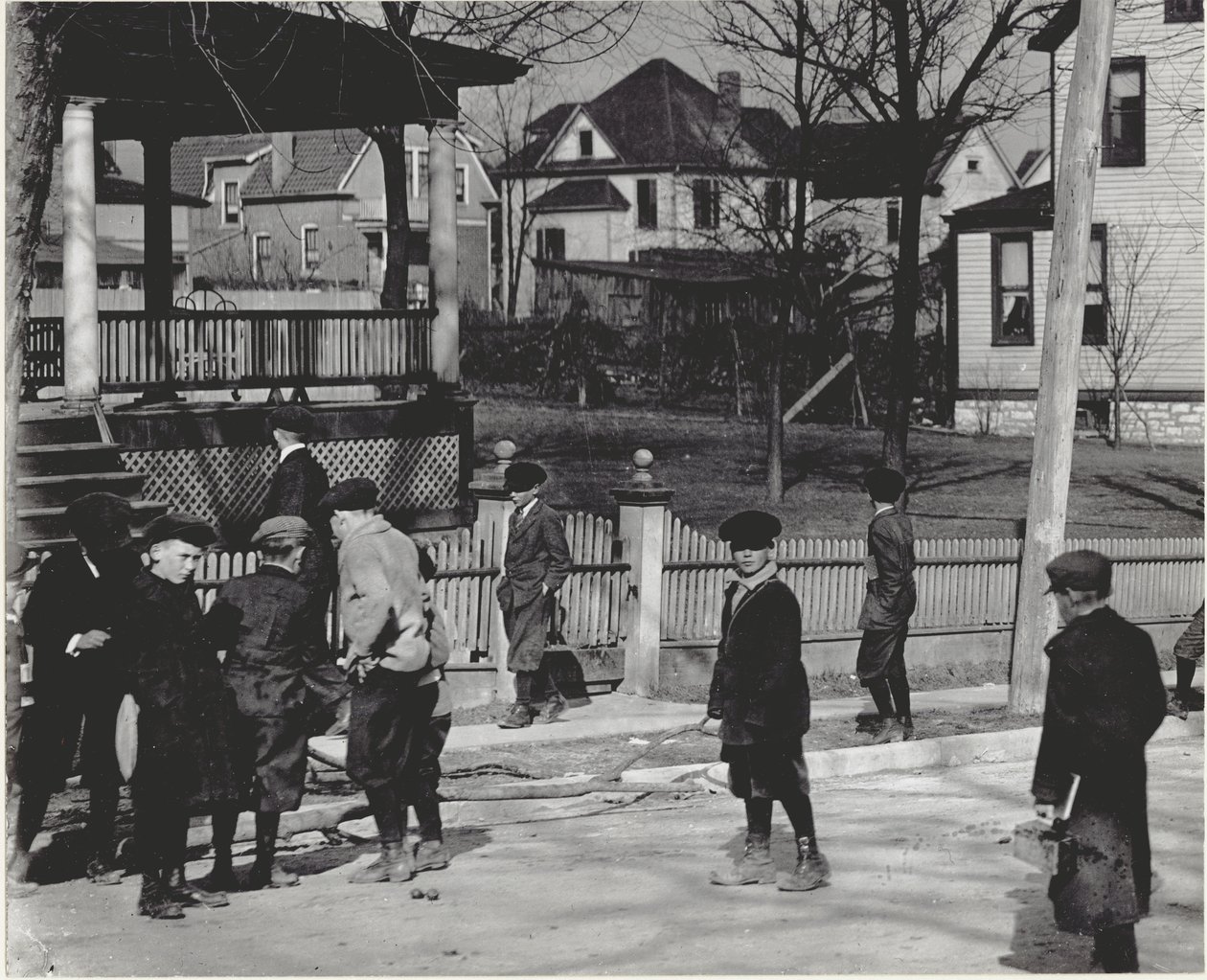 A Group of Boys in Winter Coats Standing on an Unidentified Street Either Before or After a School Day. by Unbekannt