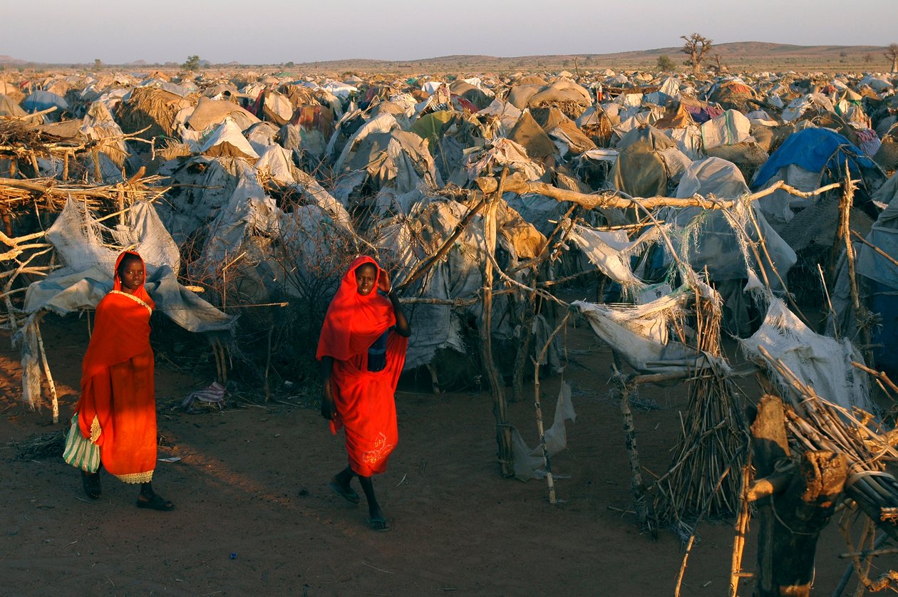 Women in Bright Red Clothes Walking Through Otash Camp for Internally Displaced People by Unbekannt Unbekannt