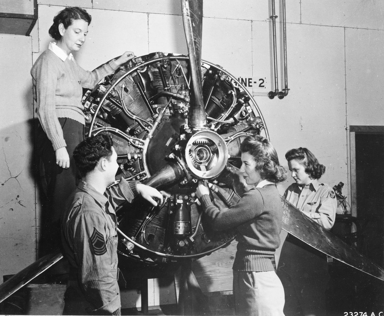 Wasps learn where the power comes from in the B-17 Flying Fortress engine while attending B-17 pilot training at Lockbourne AAB, Working on the propeller mechanism, while a crew chief looks on, they are Patricia Bowser, Ann Waldner and Frances Green by Benjamin Baud