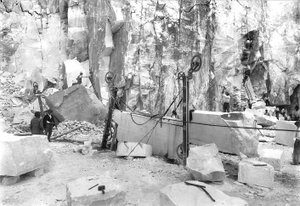 Excavators at work at a marble quarry in the Apuan Alps, Tuscany. In the foreground there are blocks of marble already squared off.