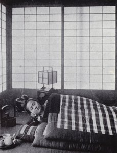 Girl asleep between wadded quilts with a wooden pillow by American Photographer (after)