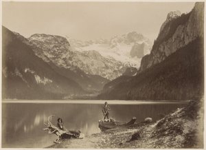 View of a Lake and Surrounding Mountains with a Man Standing in a Boat, Probably in the Alps