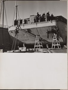 A group of men work on a docked boat by Arnold Eagle