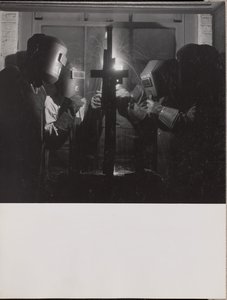 Four men wearing welding helmets welding a piece of metal