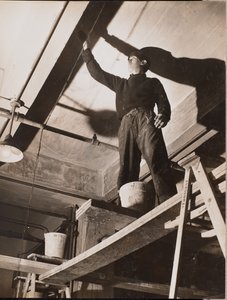 Man standing on wooden scaffolding painting a ceiling by Arnold Eagle