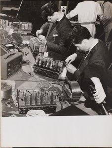 Two young men wearing blazers work on radios