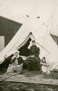 Sister Eleanor Wibmer Jeffries and Sister Nellie Constance Morrice outside their tent at No 3 Australian General Hospital with flowers picked from the bank of the Somme, c. June 1917 by Australian Photographer