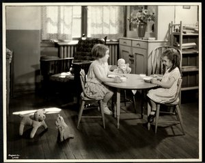 Two blind visually impaired girls eating at a small table with doll at the New York Association for the Blind, 111 East 59th Street, New York, 1933