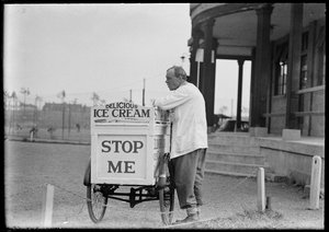 An Eldorado ice cream seller standing beside his tricycle cart outside a pavilion