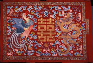 A Chinese Hanging of Red Wool with a Central Character in Gilt Thread Flanked by a Phoenix and a Dragon