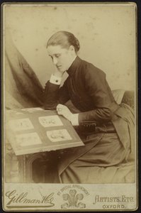Figure of a woman sitting inspecting a photograph album