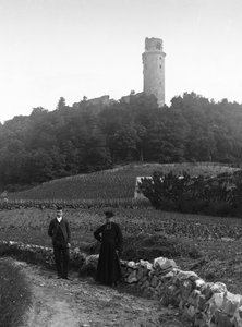 The country cure, accompanied by a young man, posing in front of the tower of Montlhery in Essone. Photography late 19th century. Ducos Collection