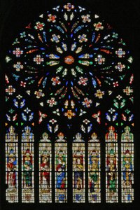 Window w237, the west rose window, depicting the Lamb of the Apocalypse at the center surrounded by 12 angel musicians; coats of arms that include Montmorency-Laval, Bertrand Duguesclin and Oli