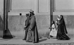 Russian Orthodox priest strolls sidewalk followed by his wife and two children in Moscow