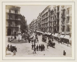 View of Via Roma in Naples with a Statue, Shops, Horse Carriages, and Passersby by Giorgio Sommer