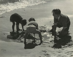 Three kids playing with sand at the beach