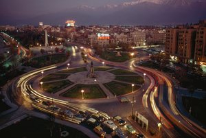 Car, city lights illuminate Plaza Baquedano, Santiago, Chile