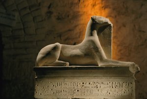 Limestone statue of the jackal god Anubis crouched on a base shaped like a sarcophagus by Kenneth Garrett