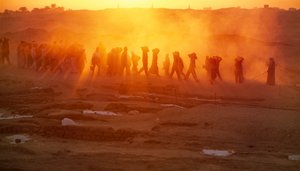 Workers labor to carry materials at archaeological excavation at Abydos, 2005