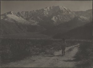 Woman Walking on Path Towards Mountains