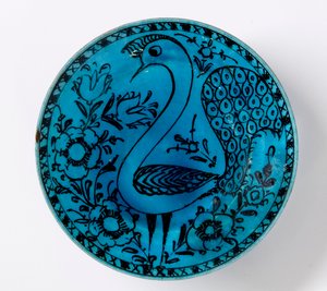 A 19th century Persian pottery dish depicting a peacock on a turquoise background by Persian School