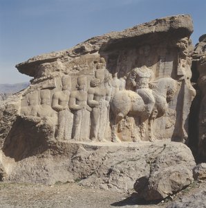 Rock relief depicting Shapur I and his family wearing heraldic emblems on their hats, with a tri-lingual inscription on the horse in Greek, Parthian and Middle Persian by Sasanian
