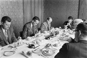 Businessmen praying before beginning to eat lunch at a church fundraising meeting