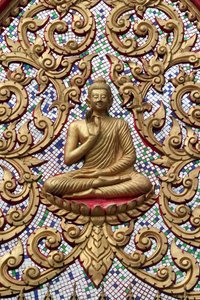 Entrance door ornamented with gold reliefs. The Teaching Buddha depicts a particular moment in the life of the Buddha, namely, the first sermon the Buddha gave after reaching Enlightenment, Vang Vieng, Laos by Unbekannt